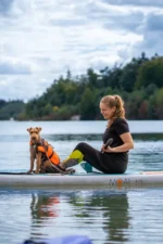 Person paddelt mit Moai 10'6 SUP-Board und Hund auf dem Wasser